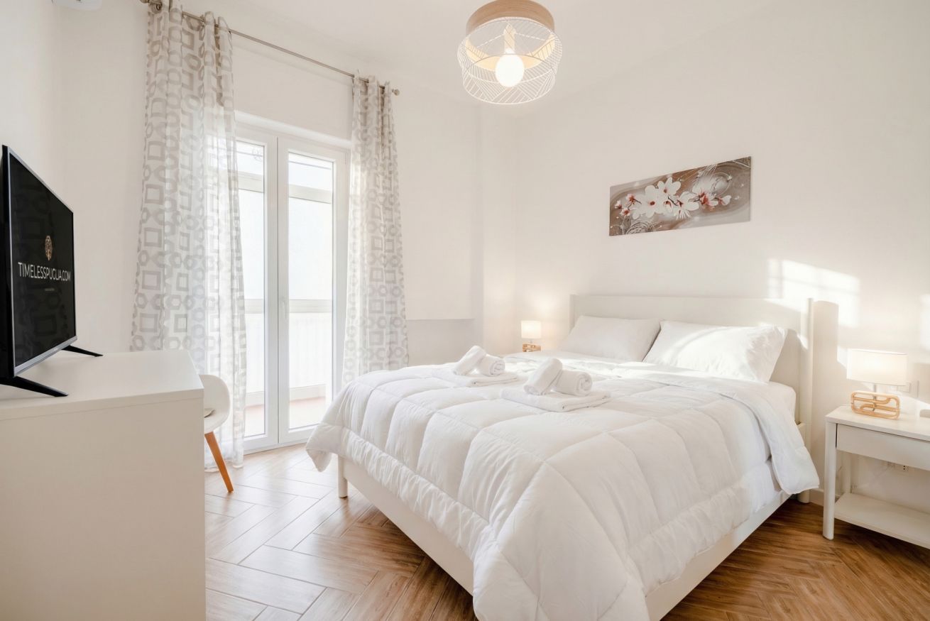 Une chambre d’hôtel avec un lit, un bureau, une télévision et une fenêtre avec des rideaux.
