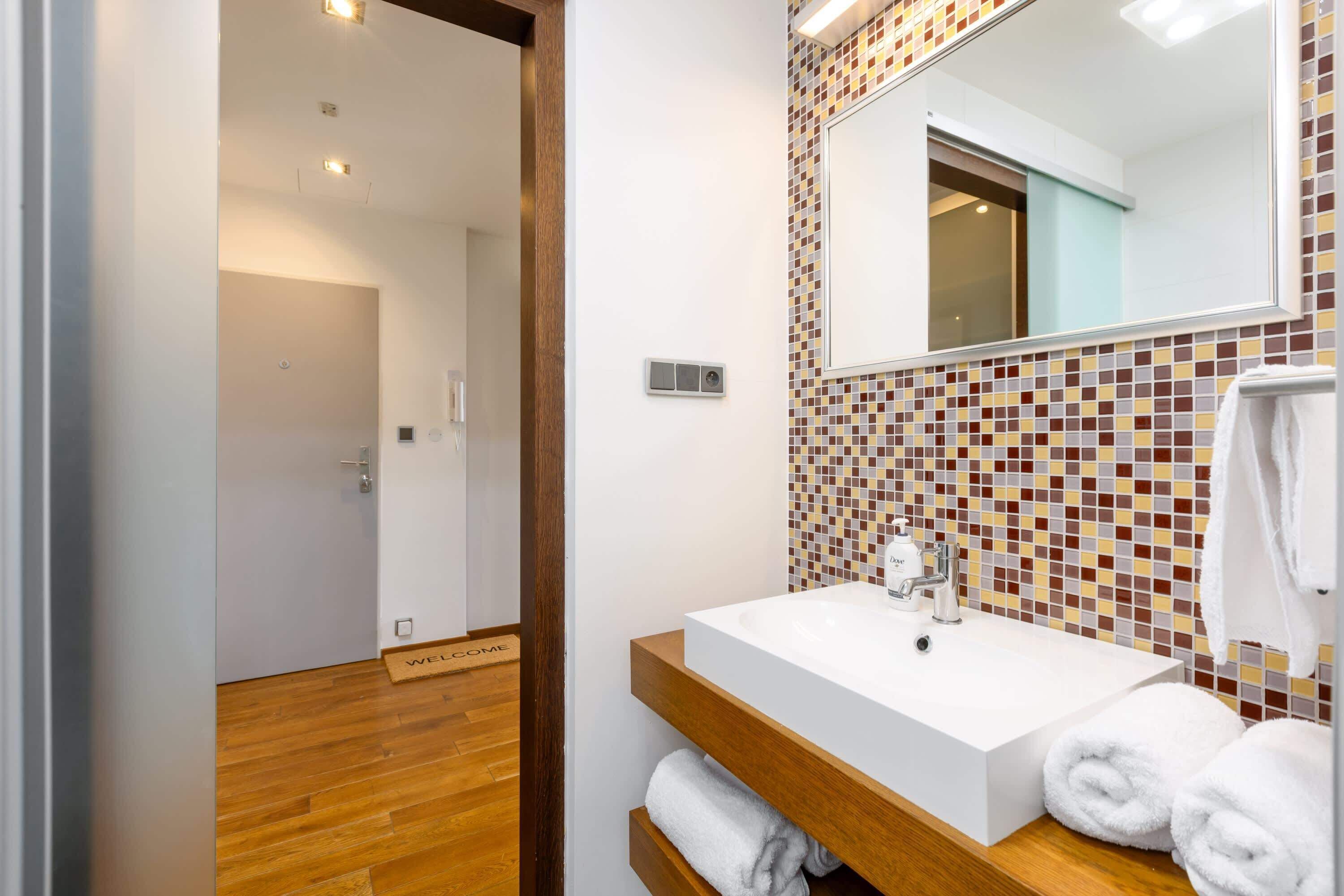 A bathroom with a white sink, a mirror, and a tiled backsplash.