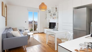 Una cocina moderna con un refrigerador grande, muebles blancos y una zona de comedor con una mesa y sillas blancas.