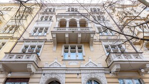Un edificio de varios pisos con detalles arquitectónicos ornamentales, incluyendo ventanas en arco y molduras decorativas.