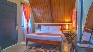 Een slaapkamer met een bed, nachtkastje, lamp en een bureau met een computer.