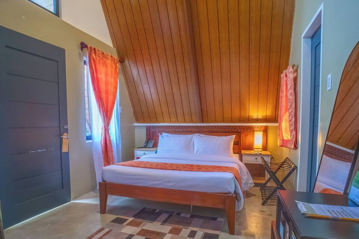 Une chambre à coucher avec un lit, une table de chevet, une lampe et un bureau avec un ordinateur.