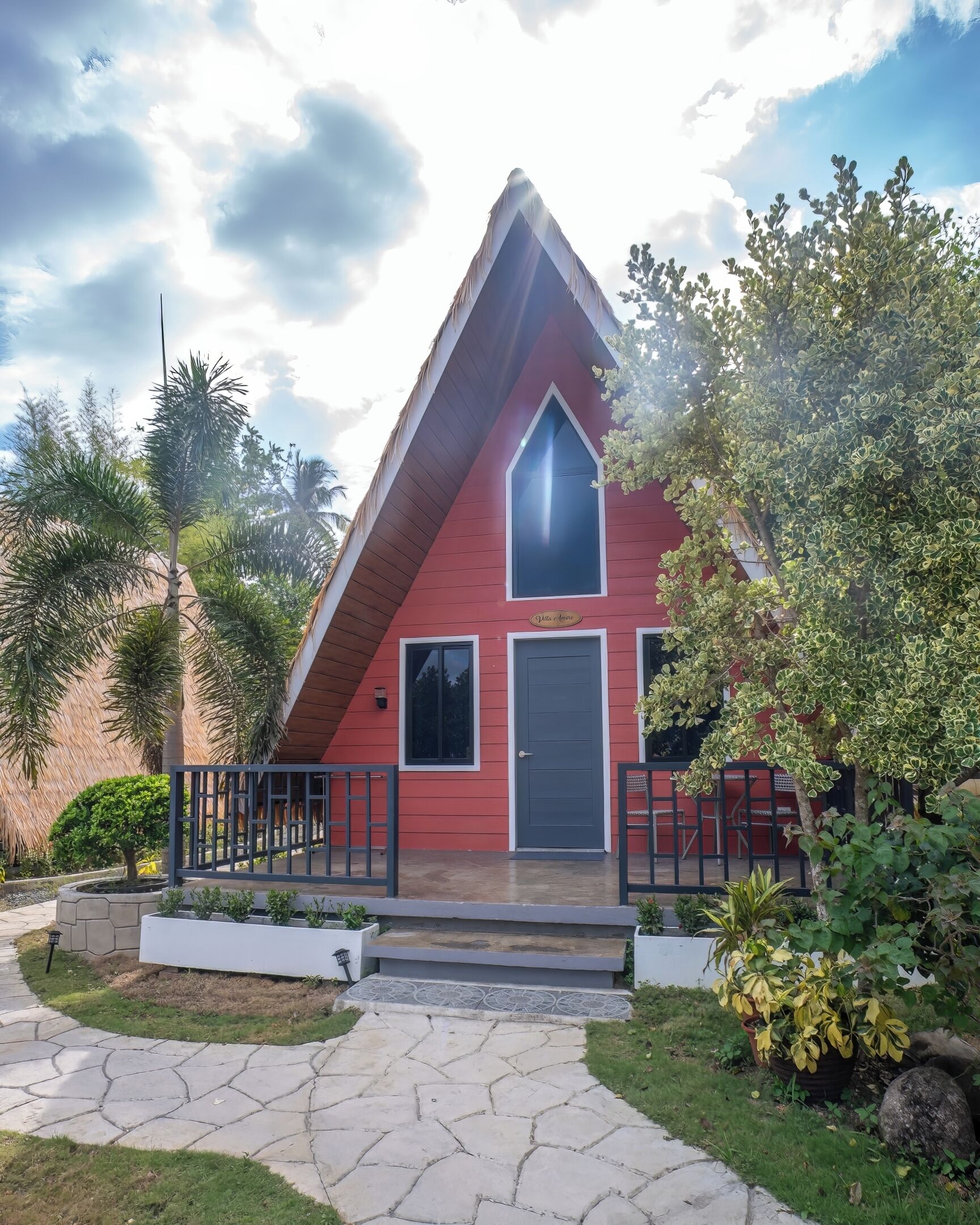 A red building with a triangular roof, a front door, and a small porch with a railing.