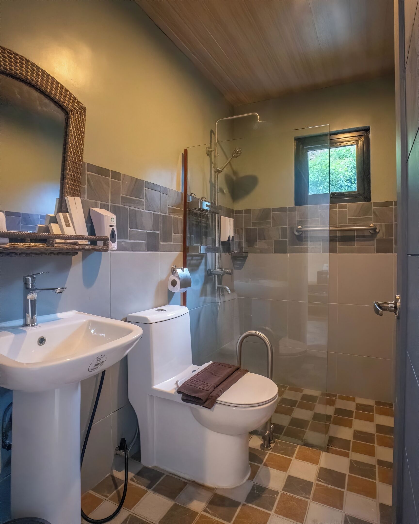 A bathroom with a sink, toilet, shower, and a window.