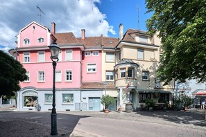 Eine Straße mit einer Reihe von Gebäuden, darunter ein rosafarbenes Gebäude mit vielen Fenstern und ein Geschäft an der Ecke.