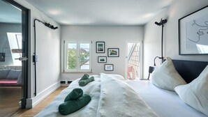 Une chambre à coucher moderne avec un grand lit, une porte-fenêtre coulissante et une vue sur l’extérieur.