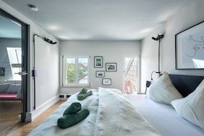 Ein modernes Schlafzimmer mit einem großen Bett, einer Schiebetür aus Glas und Blick ins Freie.