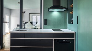 Une cuisine moderne dotée d’un lave-vaisselle encastré, d’un évier en acier inoxydable et d’une hotte noire.