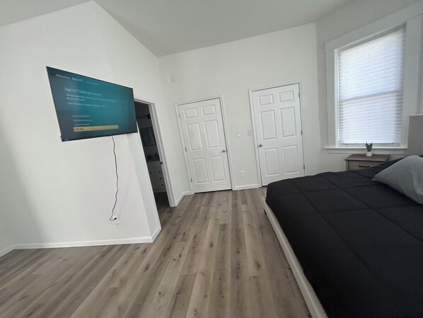 A bedroom with a bed, a desk, and a window.