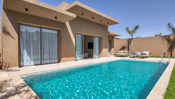 Ein moderner Poolbereich mit klarem Pool, einer überdachten Lounge-Ecke mit Liegestühlen und einer großen Glaswand als Eingang.