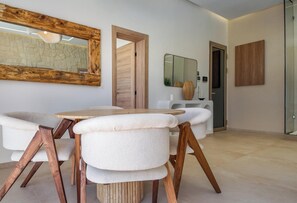 A modern dining area with a wooden table and chairs, a large mirror, and a stone-textured wall. - Bungalow Gueliz - heated swimming pool not overlooked (Marrakech)