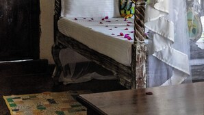A rustic wooden bed with a canopy, a wooden door, and a patterned rug. - RIZIKI YANGU HOUSE-4 BEDROOM LUXURIOUS HOUSE (Malindi)