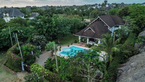 A house with a swimming pool surrounded by lush greenery and a thatched roof. - RIZIKI YANGU HOUSE-4 BEDROOM LUXURIOUS HOUSE (Malindi)