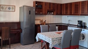 Una cucina funzionale con angolo ristoro, dotata di frigorifero, fornelli e lavatrice.