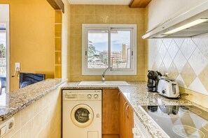Une cuisine compacte équipée d’un lave-linge intégré, d’une fenêtre avec vue et d’une cuisinière.