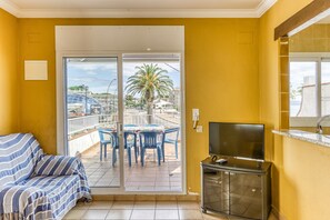 Une pièce comprenant un canapé, un téléviseur et un balcon avec des chaises et une table.