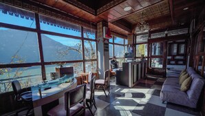 A room with large windows, a checkered floor, a sofa, and a desk with chairs. -  Hotel Silverton (180 lake view)  (Nainital)