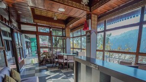 A reception area with a checkered floor, wooden ceiling, and large windows offering a mountain view. -  Hotel Silverton (180 lake view)  (Nainital)