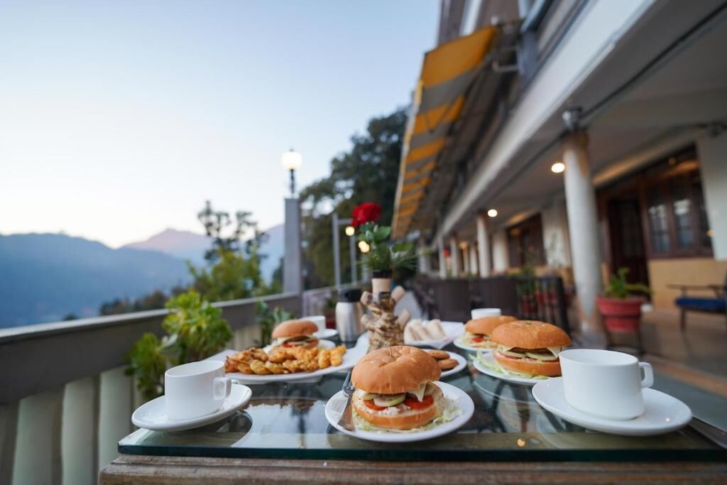 Una mesa de comedor con comida y bebidas en una terraza con vista a la montaña.