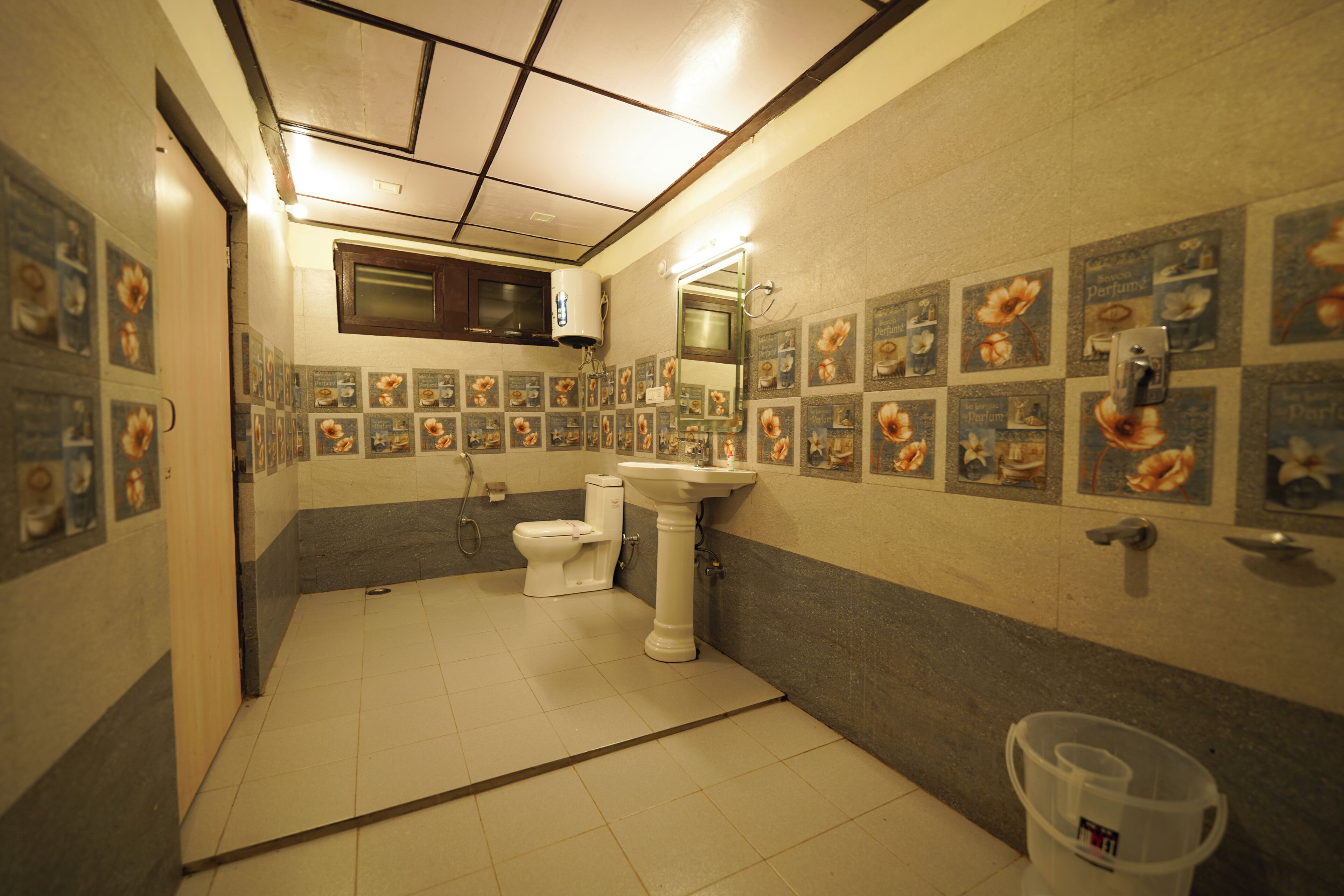 Baño con inodoro, lavamanos y ducha. Las paredes están decoradas con motivos florales.