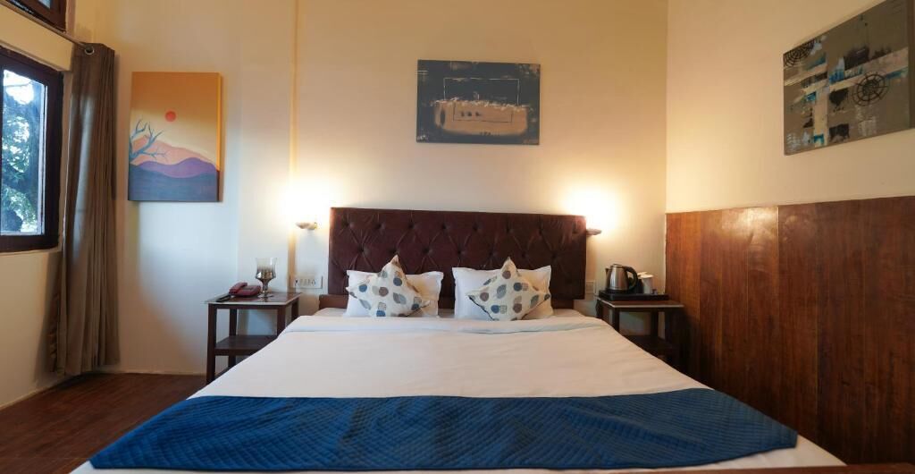 A bedroom with a large bed, two nightstands, a wooden headboard, and artwork on the walls.