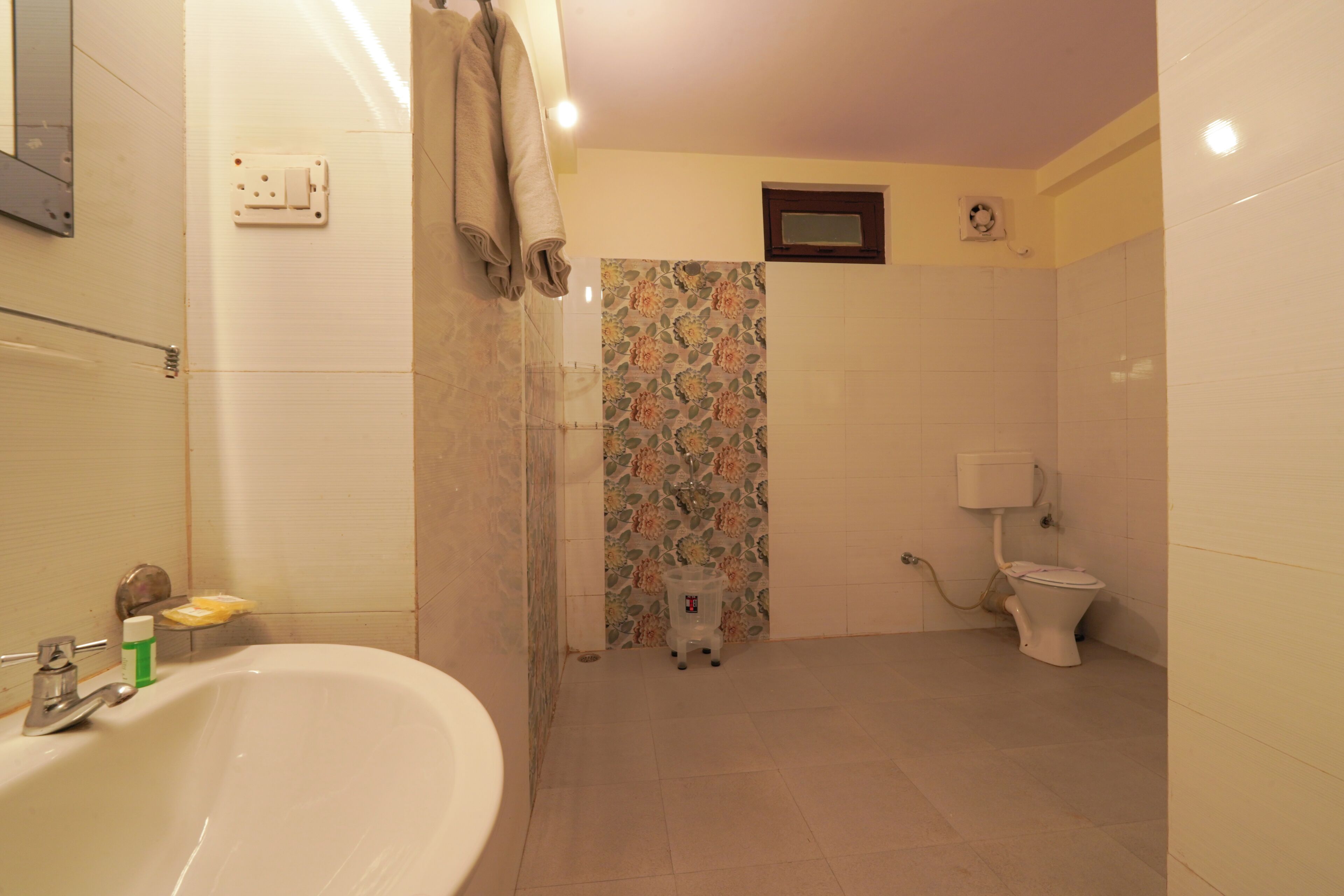 A bathroom with a bathtub, toilet, shower, and a small trash bin.