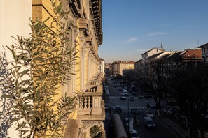 Une vue de rue avec des bâtiments, un ciel dégagé et une route où circulent des voitures.