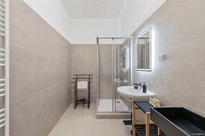 Ein modernes Badezimmer mit einer Duschkabine, einem Waschbecken mit Spiegel und einer schwarzen Badewanne.