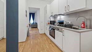 Una cocina moderna con armarios blancos, electrodomésticos de acero inoxidable y piso de madera.