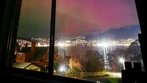 Ein Fenster mit Blick auf eine beleuchtete Stadtlandschaft bei Nacht, mit einem Farbverlauf am Himmel.