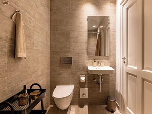 A modern bathroom with a toilet, sink, and shower area. - Shield 2 - Great Apartment in the Centre of Copenhagen (Copenhagen)