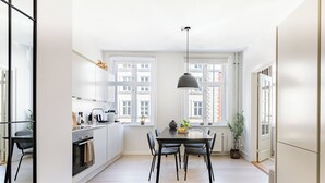 A modern kitchen with white cabinets, a dining table, and a bench. - Shield 2 - Great Apartment in the Centre of Copenhagen (Copenhagen)