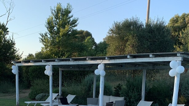 Uima-allas, jossa on aurinkotuoleja ja pergola.