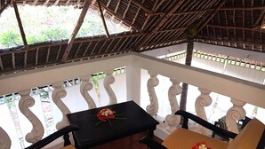 Un área de estar al aire libre con techo, que incluye una mesa y dos sillas, cada una decorada con flores.