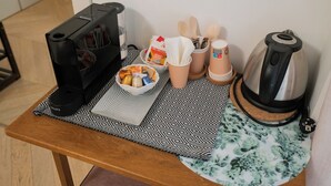 A kitchen counter with a coffee maker, a kettle, a bowl of snacks, and a basket of utensils. - Cozy room in the heart of city (Verona)