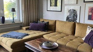 Una sala de estar con un sofá, una mesa de centro y una ventana con cortinas.