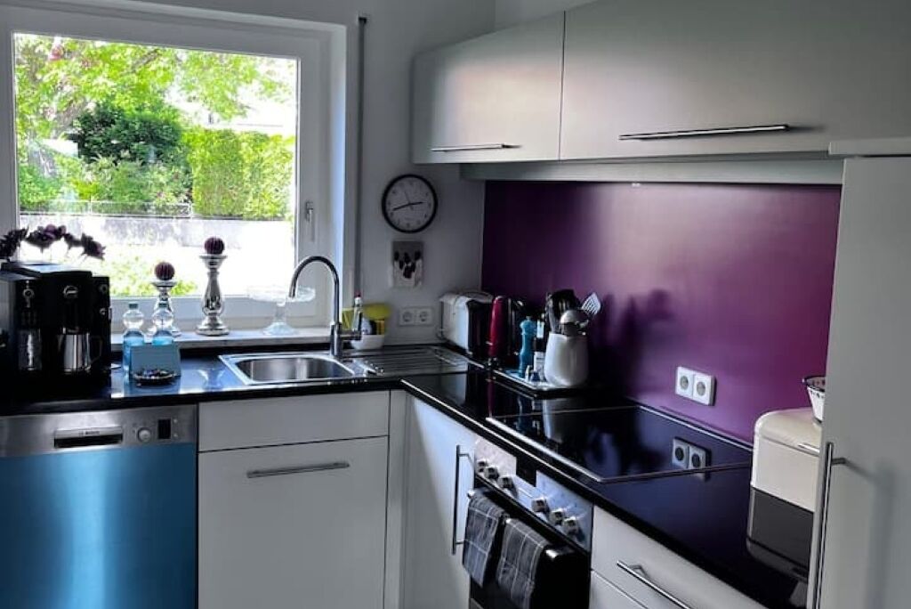 Una cucina moderna con una finestra, un orologio e una parete color viola.