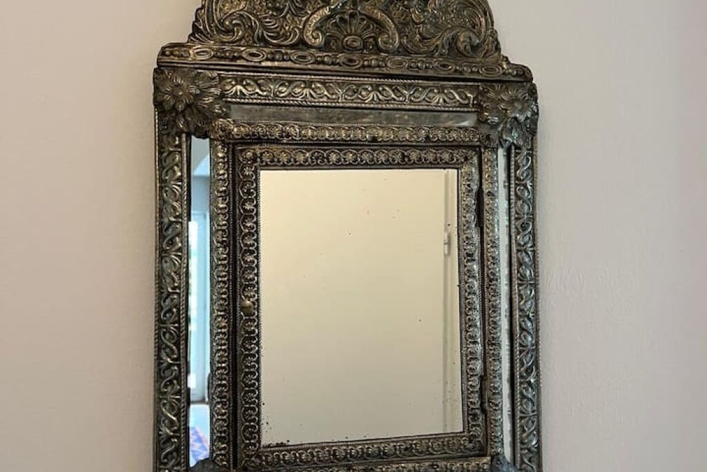A mirror with an ornate, antique frame.