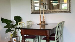 Una mesa de comedor con sillas, una planta en maceta y un espejo con un candelabro.