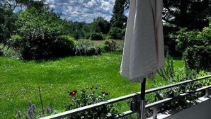 Un balcón con vistas a un jardín exuberante y un cielo parcialmente nublado.