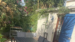An outdoor patio with a table and chairs, surrounded by plants and a blue door. - Macinaggio Vacation Home, 5 Minutes from the Beach (Rogliano)