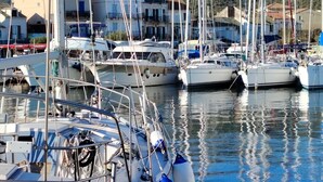 A marina with multiple sailboats docked, surrounded by buildings and hills in the background. - Macinaggio Vacation Home, 5 Minutes from the Beach (Rogliano)