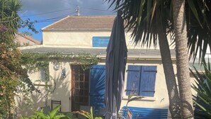 A building with a tiled roof, a blue door, and a blue window shutter. There are plants, a bench, and a potted plant in the foreground. - Macinaggio Vacation Home, 5 Minutes from the Beach (Rogliano)