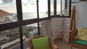 En balkon med fletstole, havudsigt og en hvid aircondition.