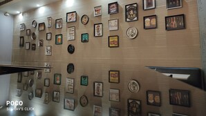 A wall with various framed items including posters, signs, and a clock. - EXPRESS FOOD PLAZA (Kolaghat)