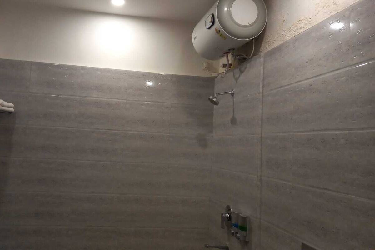 A shower area with tiled walls, a towel rack, and a handheld showerhead.