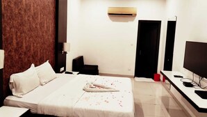A hotel room with a large bed, a TV, an air conditioner, and a desk. - EXPRESS FOOD PLAZA (Kolaghat)