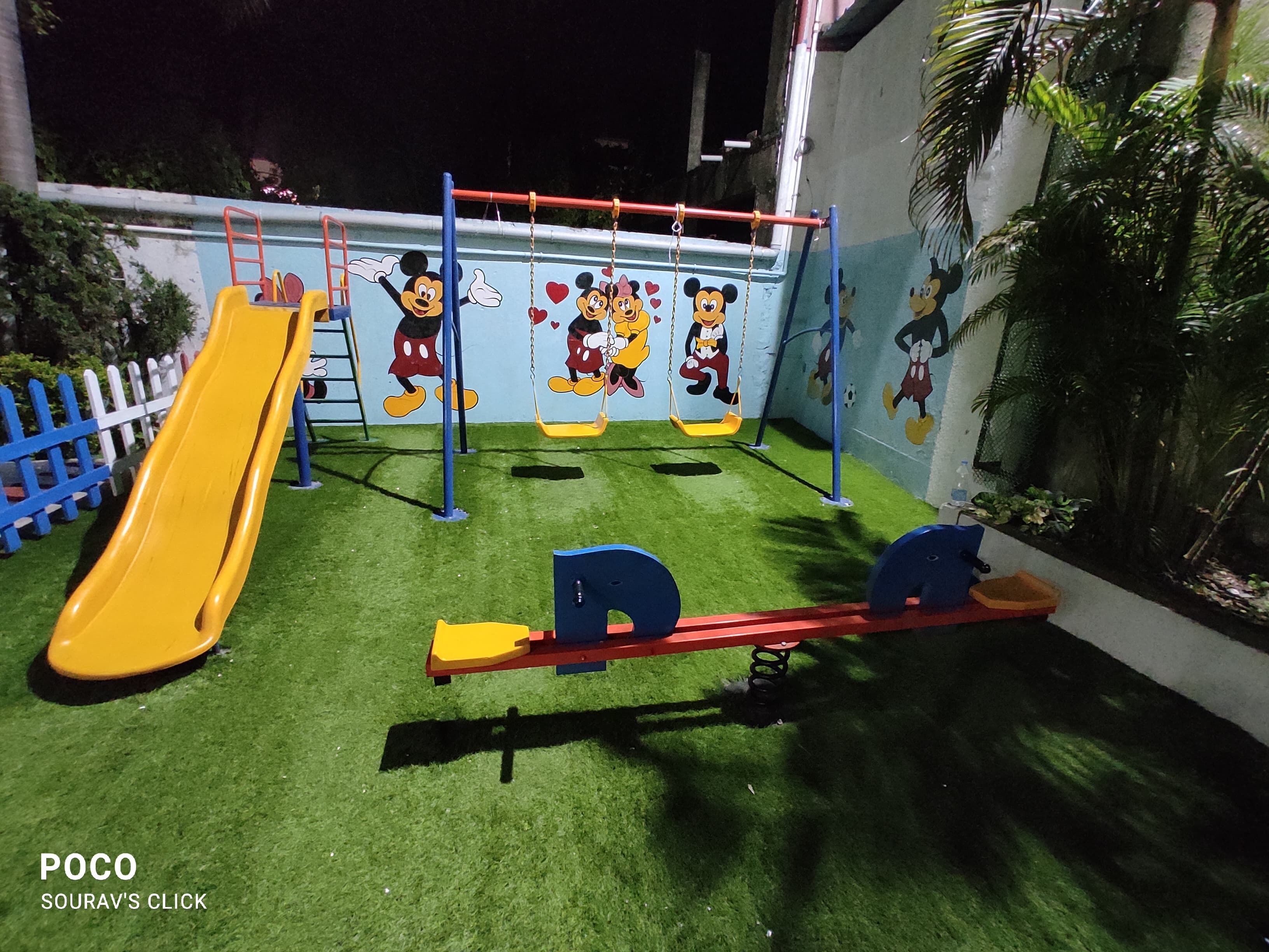 Un parque infantil con tobogán, columpios y sube y baja.