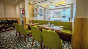 A restaurant with green booths and chairs, a patterned floor, and a fire extinguisher mounted on the wall.