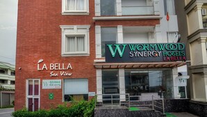 A multi-story hotel with a red brick facade, balconies, and a sign for 'Wormwood Synergy Hotels La Bella'.